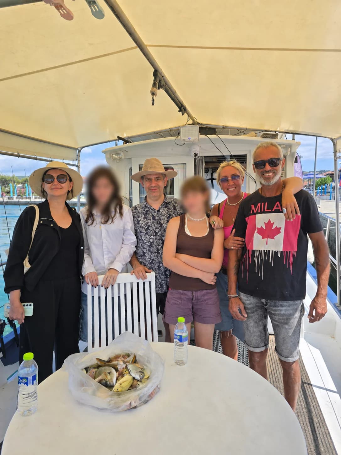 A group gathered around the day's catch with children privacy-protected