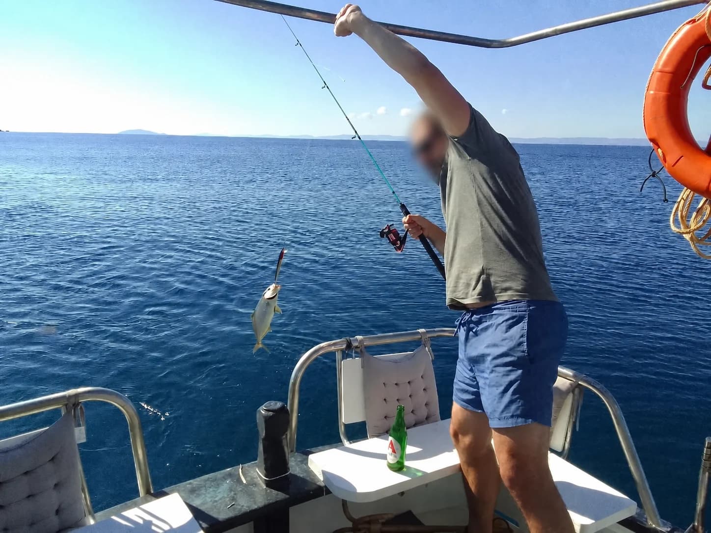 A guest holding a fish aboard with the face privacy-protected